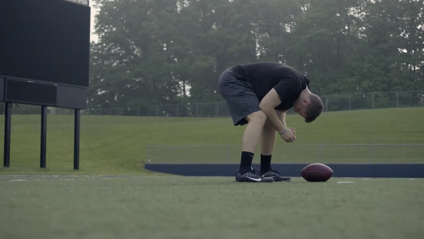 A man stretches then runs back by a football