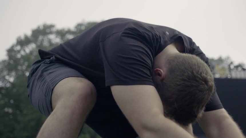 A male athlete is practicing his hiking stance outside during the day