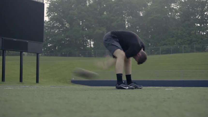 A man is practicing hiking a football