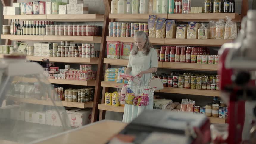 An old woman is shopping in a market during the day