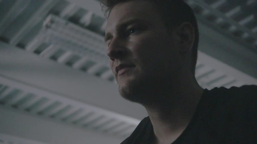 Man stands in a gym breathing heavily and looking down