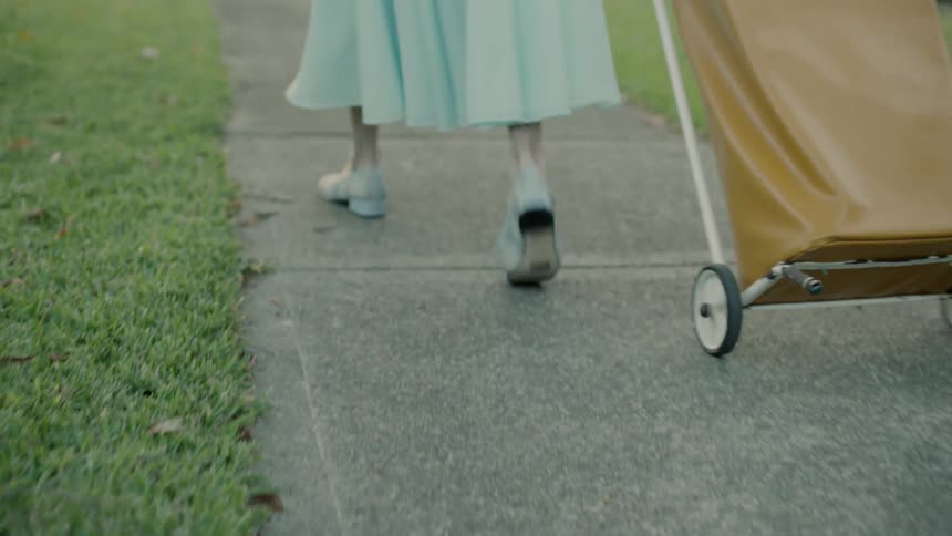 A person in a blue dress walks on the sidewalk