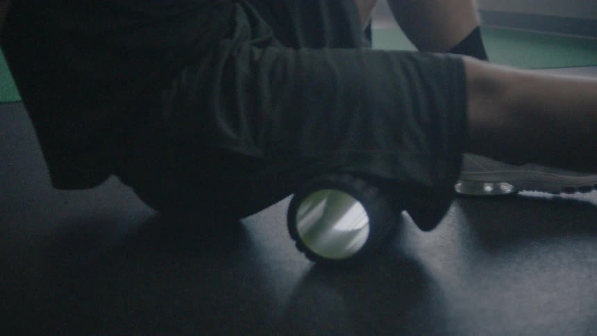 An athlete is using a roller to strengthen his calves
