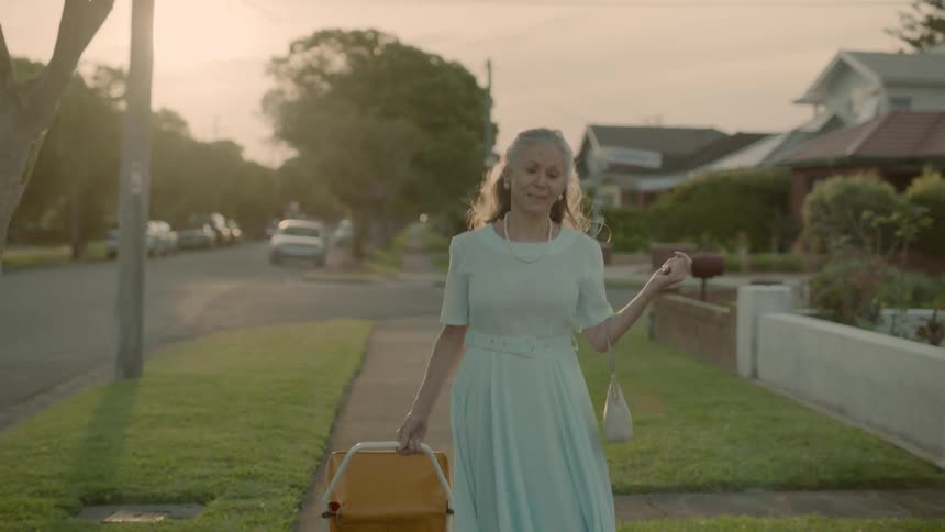 A woman is dancing down the sidewalk at sunset