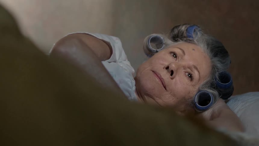 Woman lays in bed with curlers in her hair