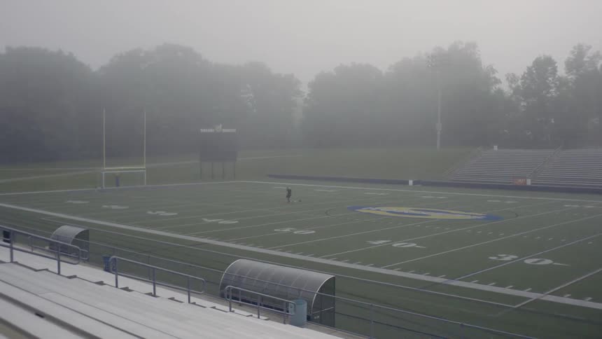 A person works out on a football field in an empty stadium