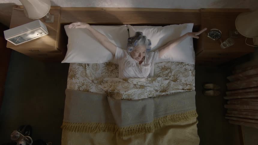 Woman laying in bed turns over and stretches