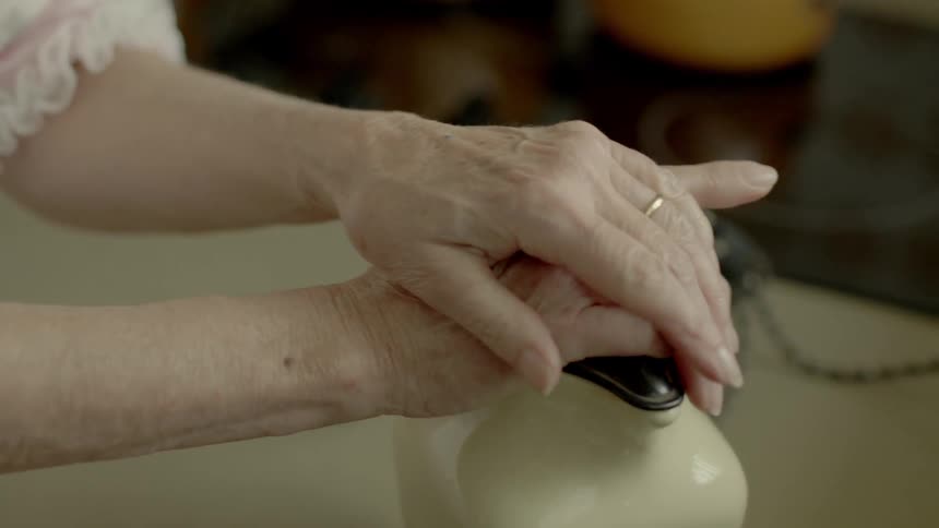 Elderly woman rests her hands on ceramic