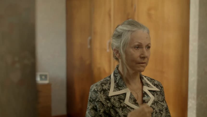 An older woman fixes her hair in the mirror