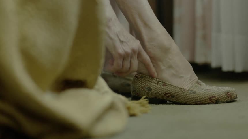 An older woman puts on shoes