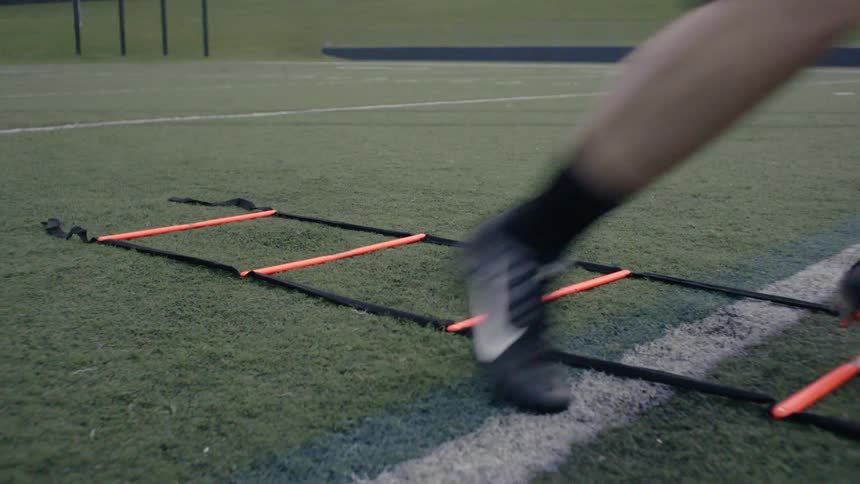An athlete is training footwork on a football field during the day