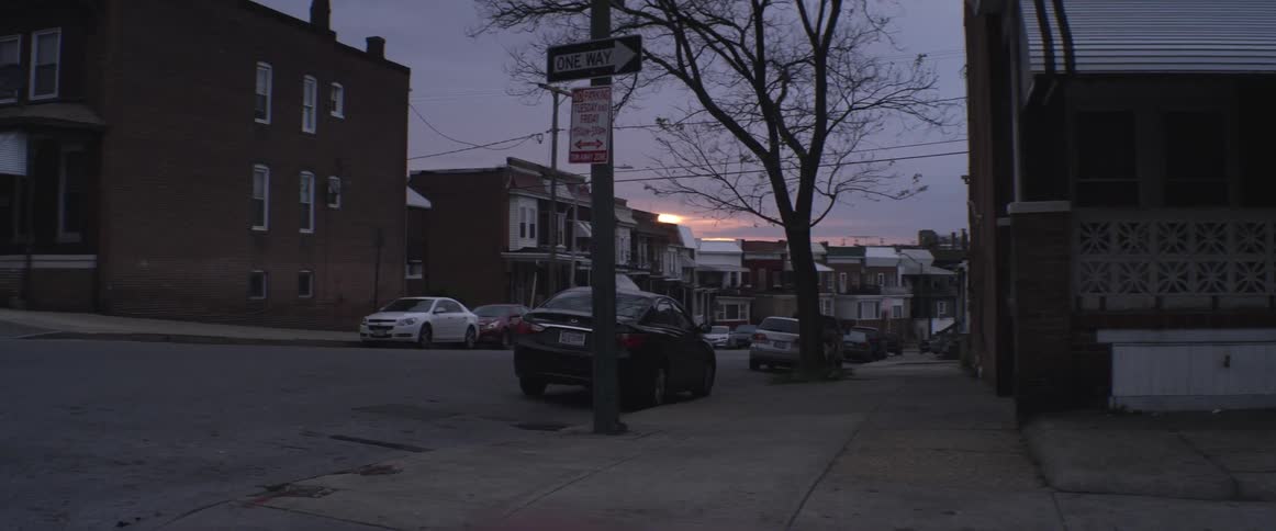 A rundown urban residential area with cars parked on the street