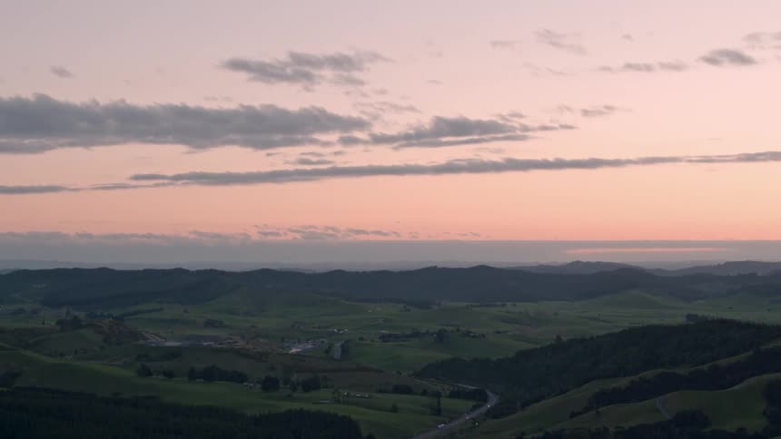 The sun sets over a grassy hill landscape