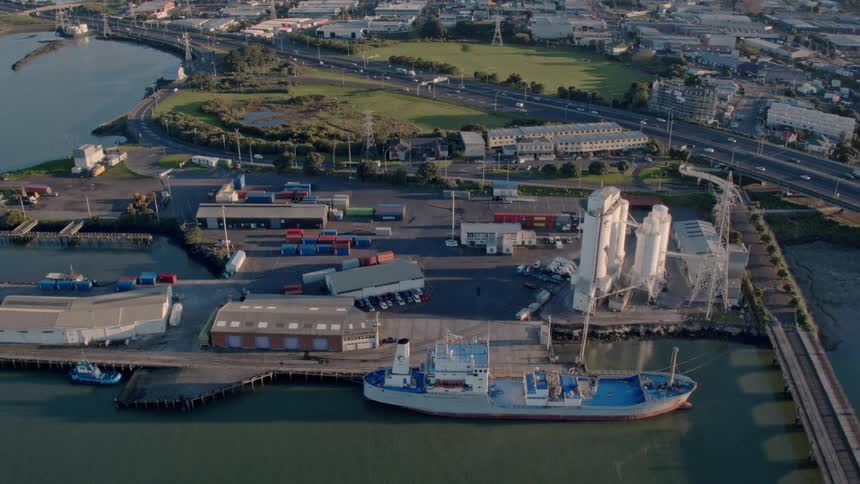A port with a large ship is being filmed from the air