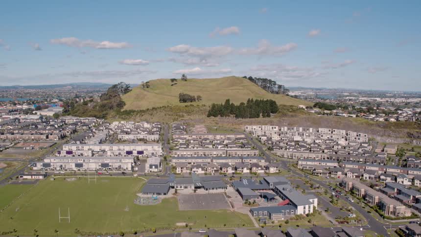 Buildings surround a grassy hill on a sunny day