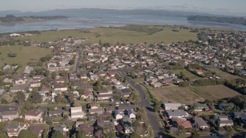 A drone is flying to and over a large hill that overlooks a town