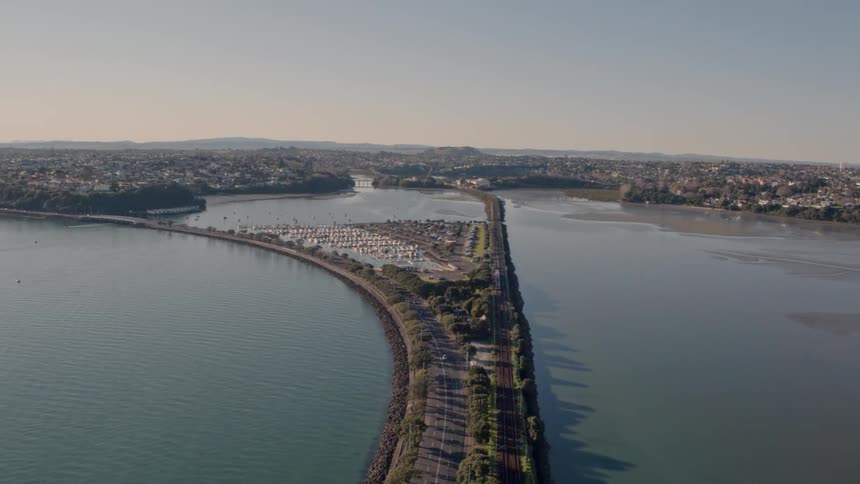 A long highway in the middle of a body of water is being filmed from a drone