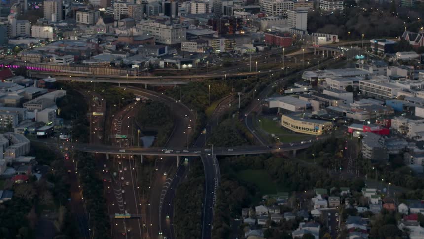 Vehicles travel on a freeway system in a city at dusk