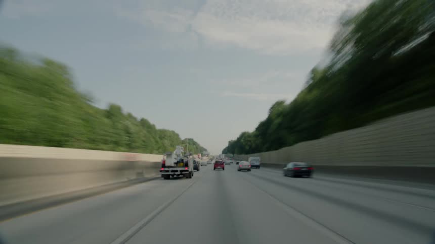 Vehicles travel along a stretch of freeway during the day