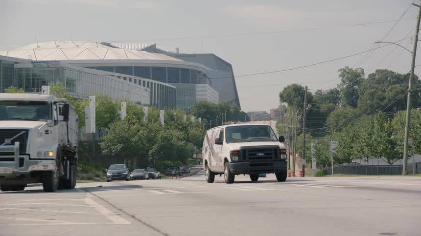 Vehicles travel on a street near a stadium during the day