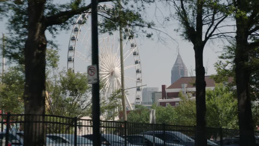A large ferris wheel is turning behind the fence