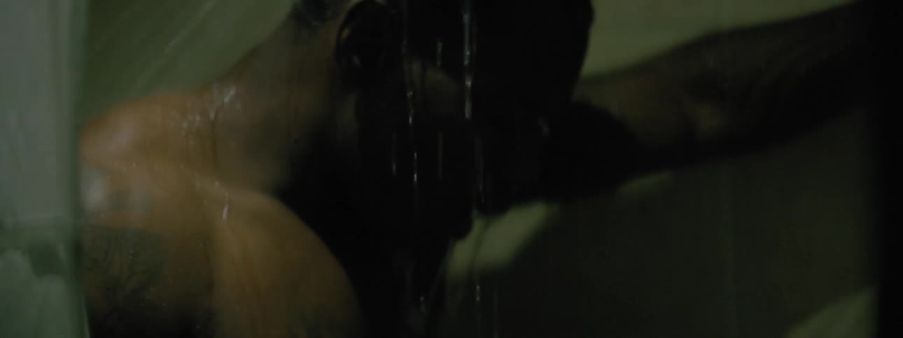 A man stands in a shower letting the water run over his head and face