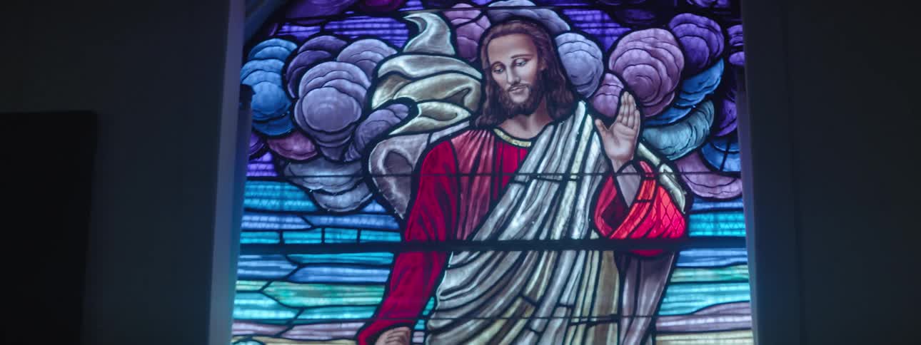 Light shines through stained glass window of jesus