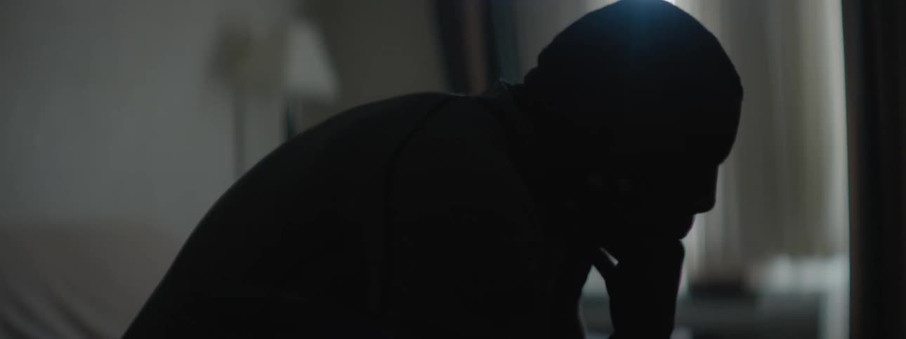 A man sitting in thought reaches up and strokes his face