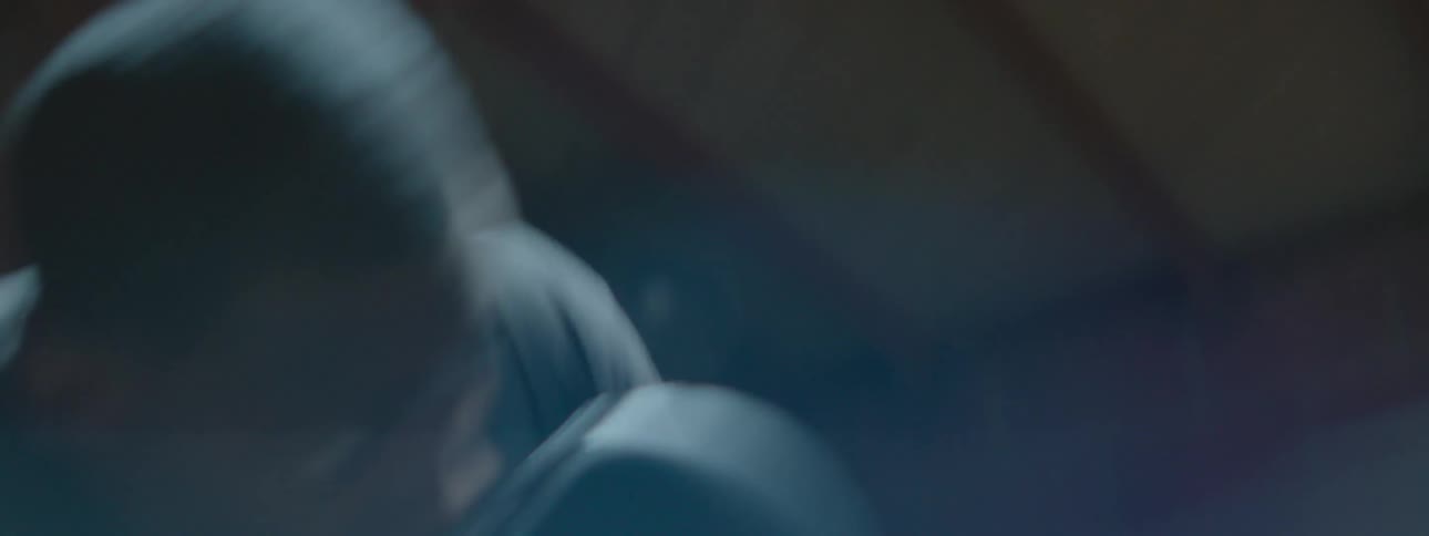 A light shines on a man shadow boxing in a dark gym