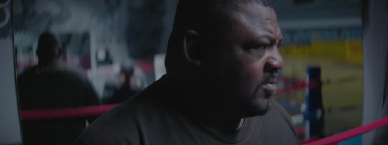 Man stands outside of a boxing ring talking
