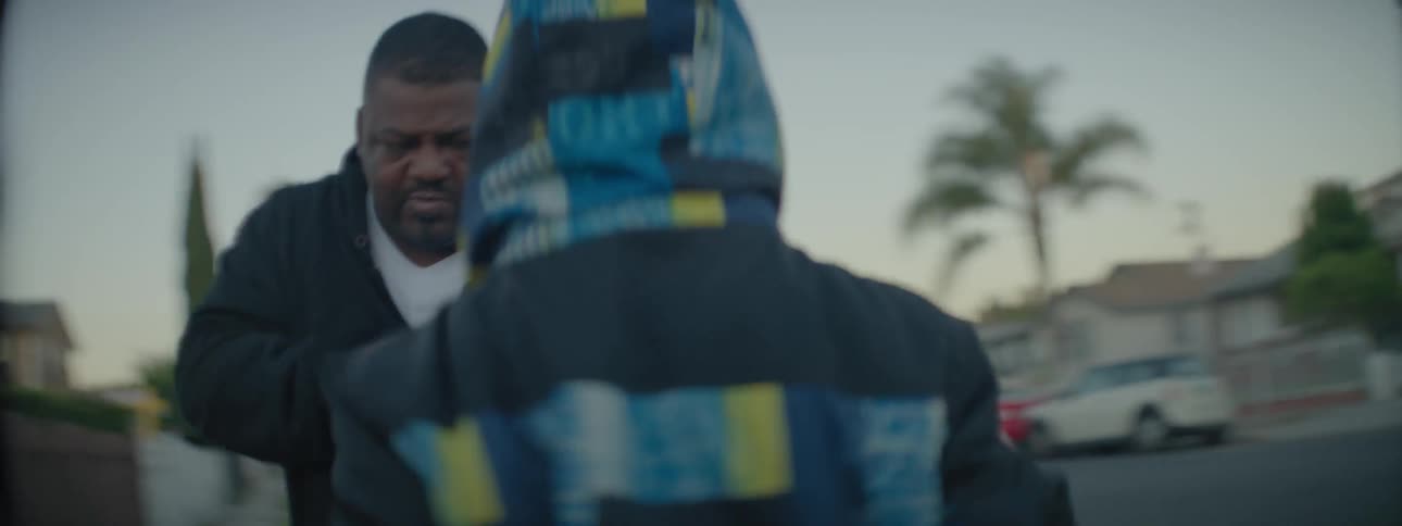 A man teaches a young boy to box on a front lawn
