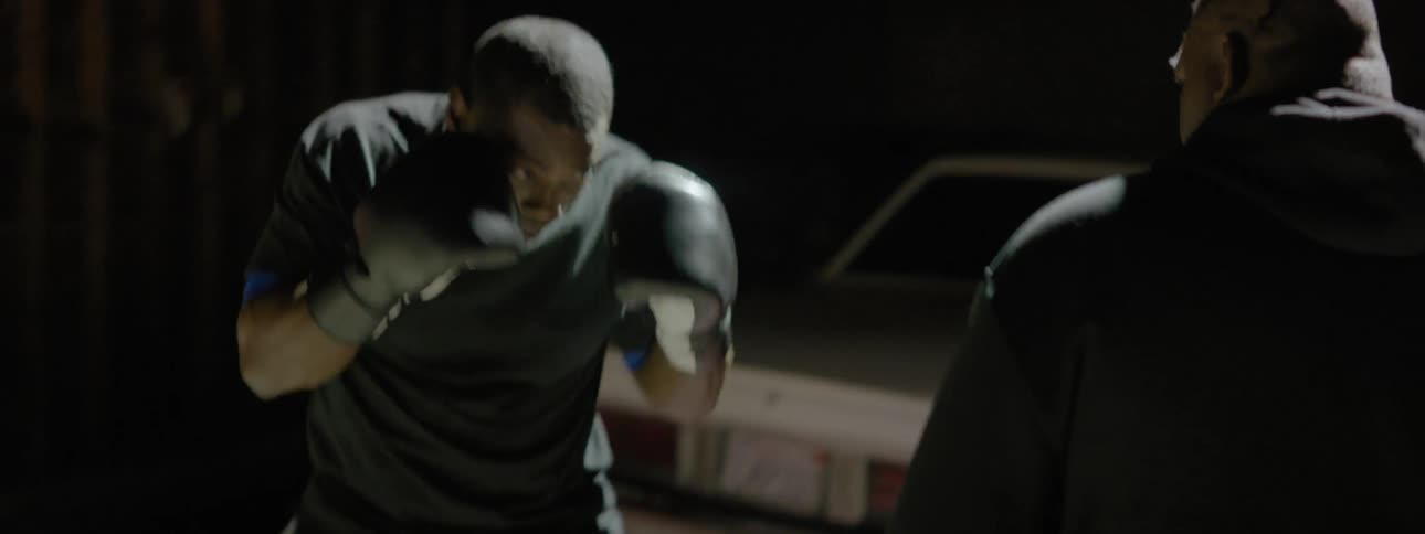 A coach is training a boxer outside at night