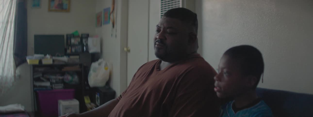 A man sitting with his son points at something as he talks