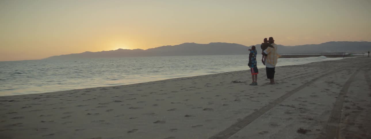 A family is standing on the beach overlooking the ocean
