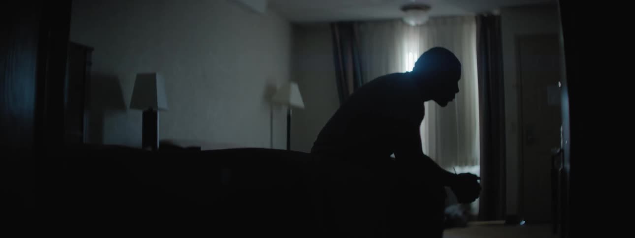 A man is sitting on the edge of his bed