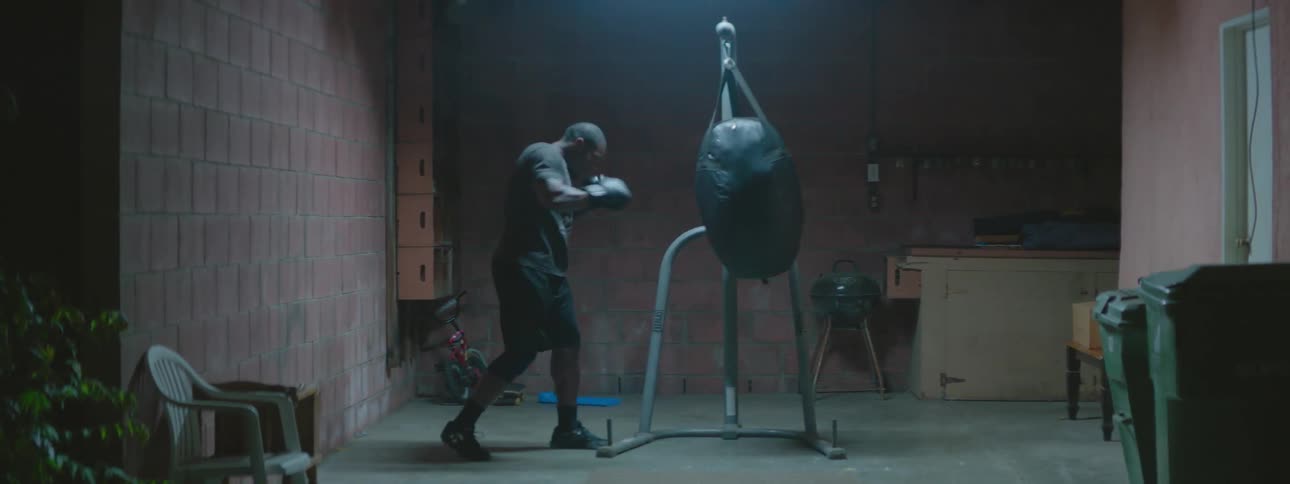 Man wearing boxing gloves punches a heavy bag