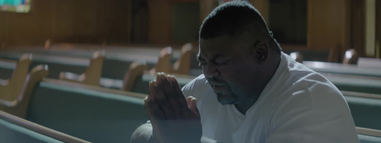 A man is sitting in a church praying