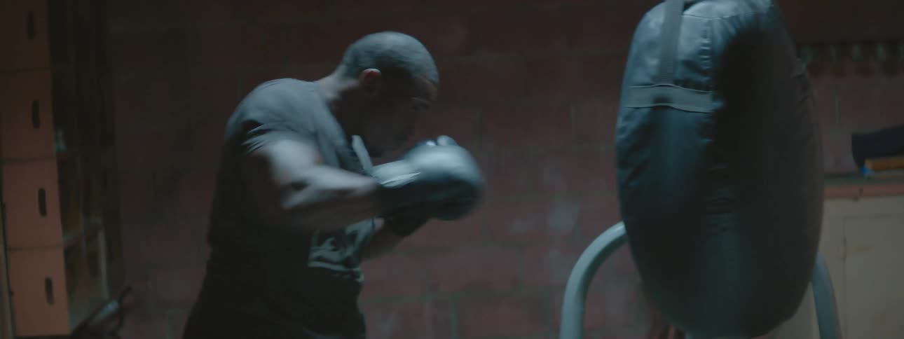 Man wearing boxing gloves punches a heavy bag