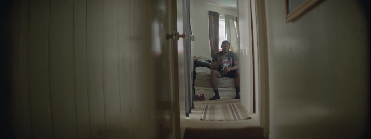 Man sits on edge of bed and stretches