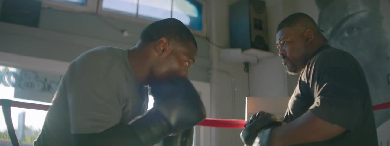 A man is practicing his boxing skills against his coach