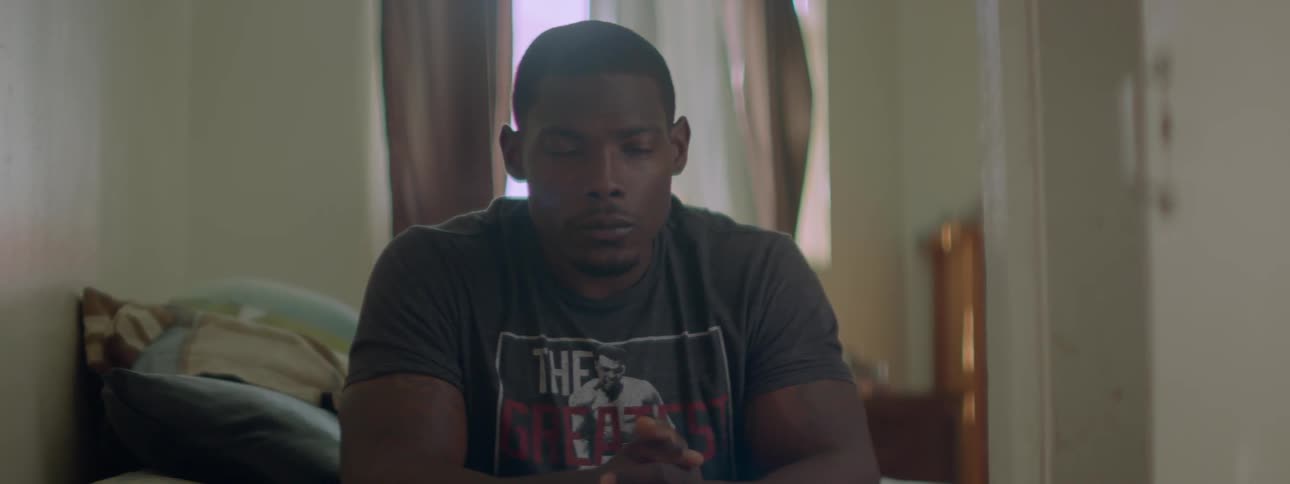 A man sits in his bedroom thinking