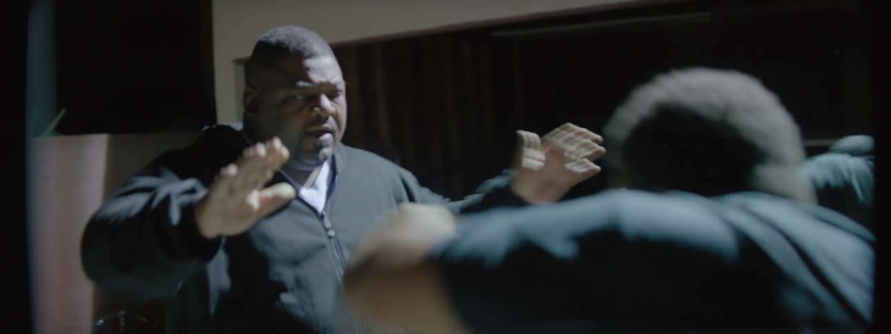 An older man is coaching two boxers outside at night