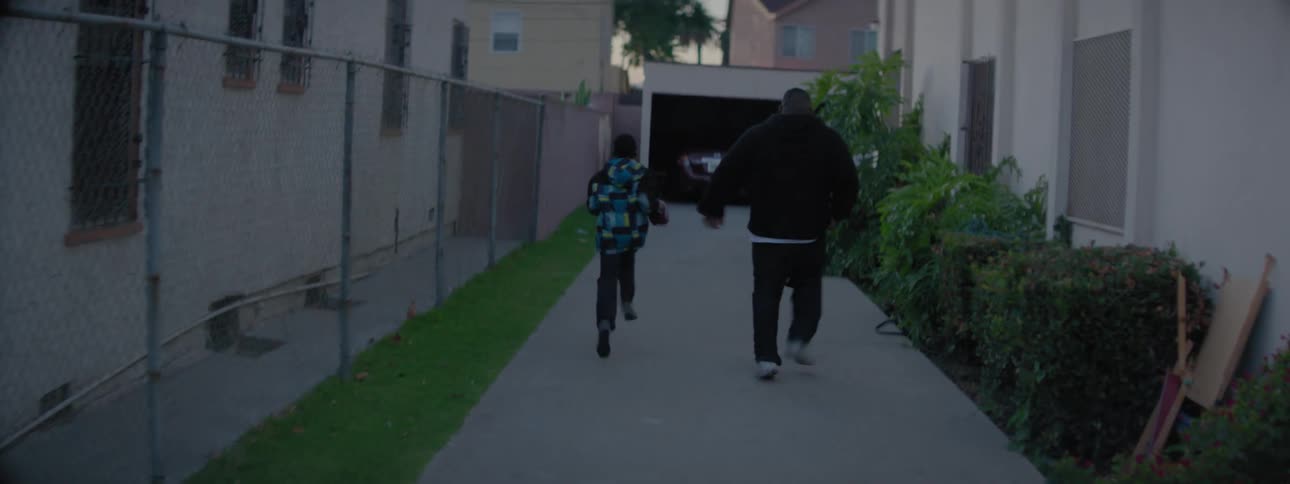 A man is foot racing his kids along a driveway