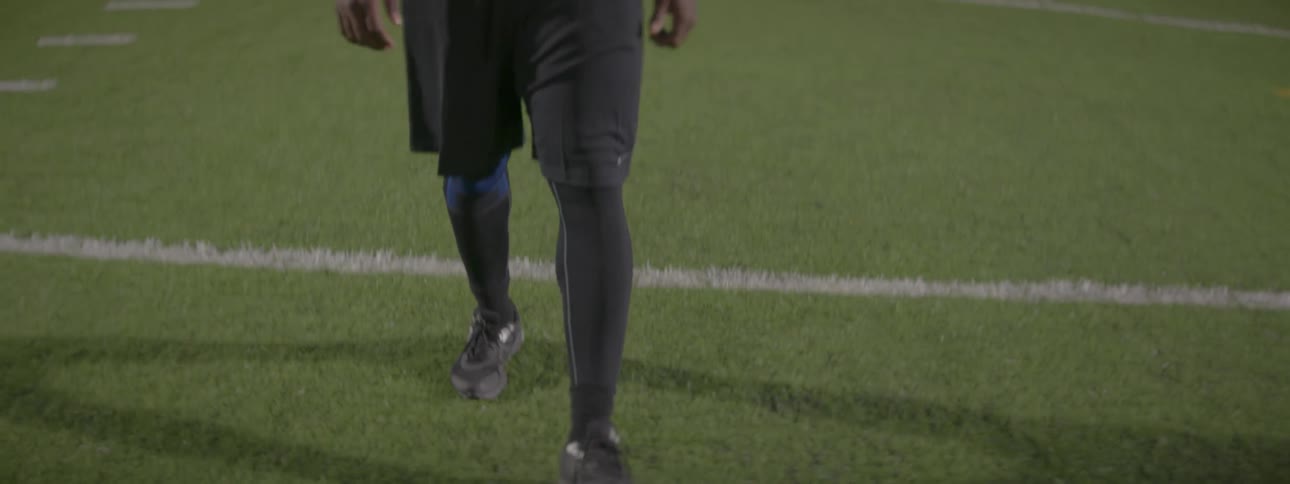 A man is walking down the middle of a football field