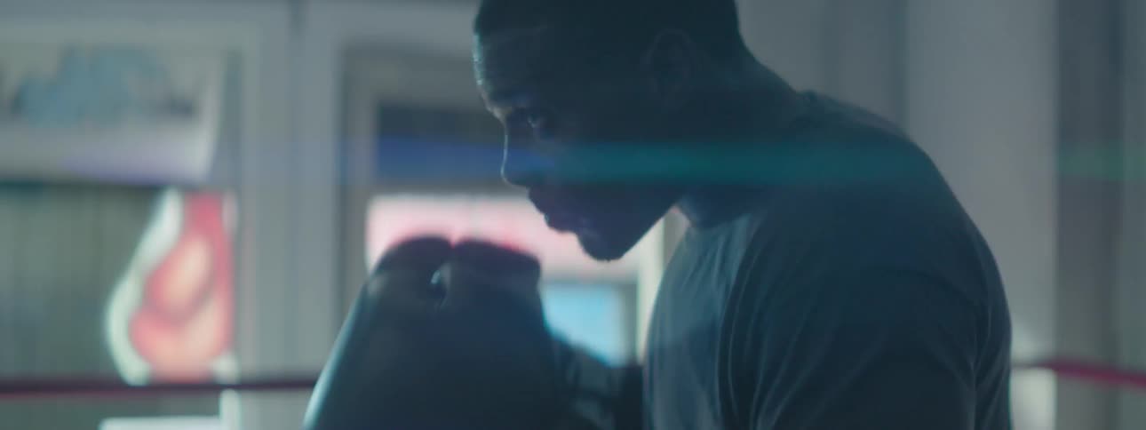 A boxer is punching forward in the dark ring