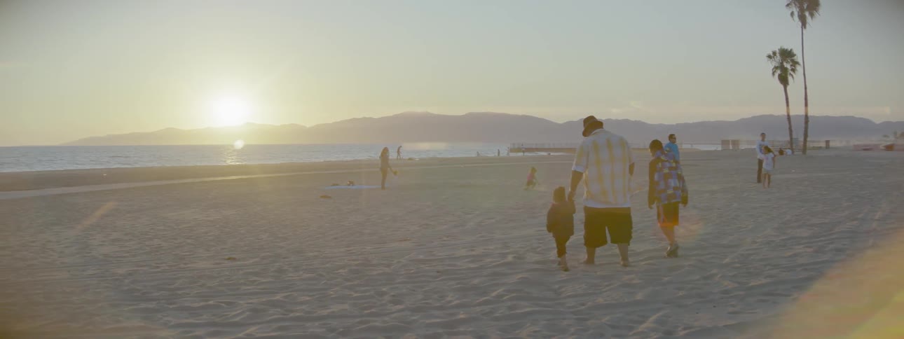 A family walks on the beach at sunset