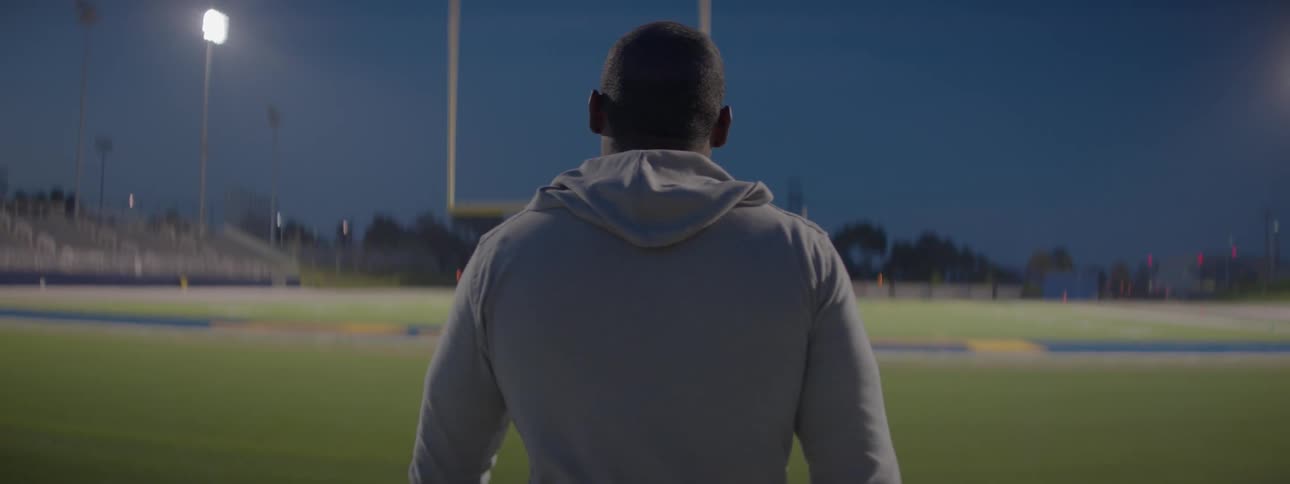 Man walks on empty football field at night