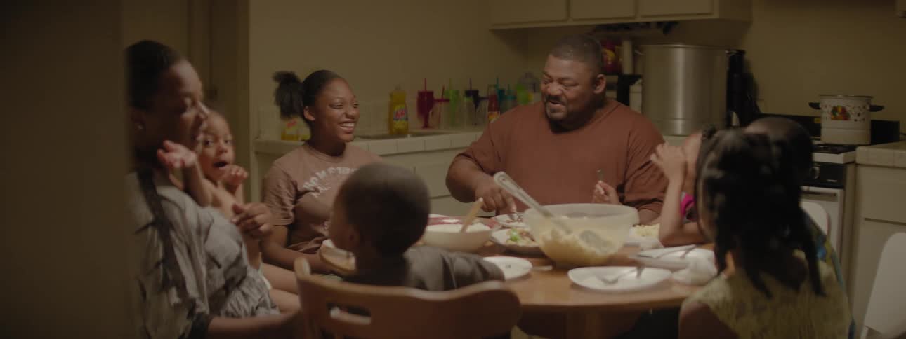 Family sits around a dinner table eating and talking