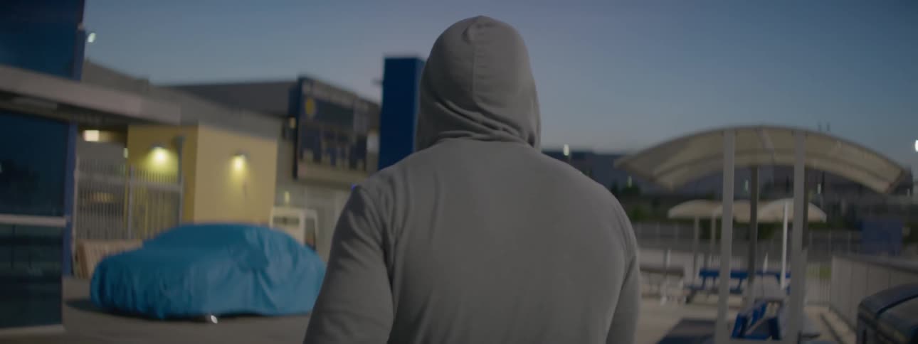 A man in a white hoodie walks past some chairs