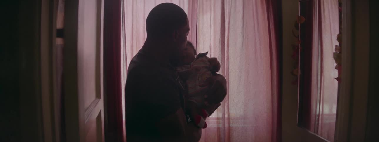 A man stands by a window and holds a baby